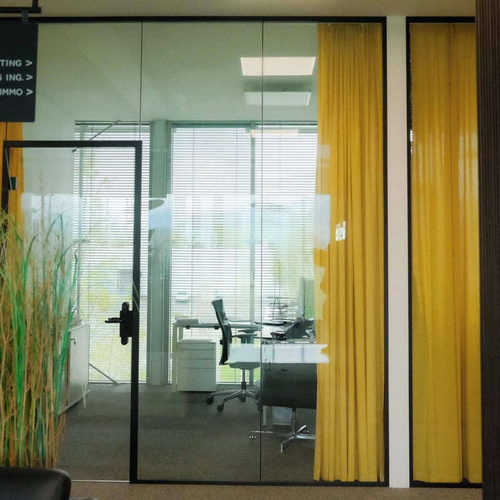 Private Office at GlessHub: glass frontage, bright workspace with mustard-yellow curtain and abundant daylight