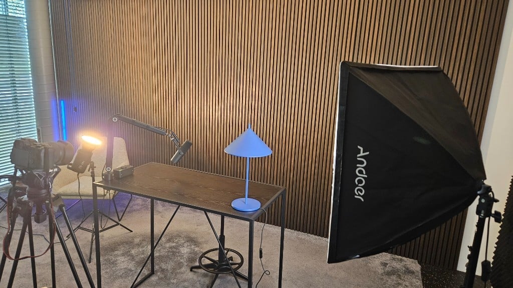 Single desk setup with camera, boom microphone, softbox and blue desk lamp