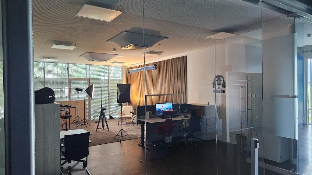 View through the glass wall into the GlessHub Studio with logo and recording area