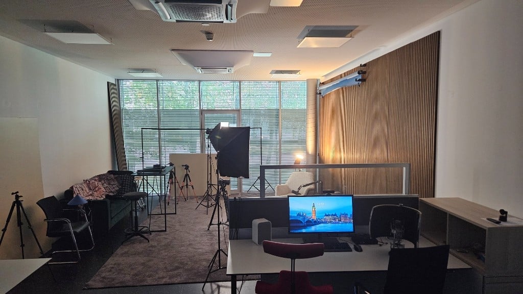 Studio with green sofa, softboxes and editing desk by the window