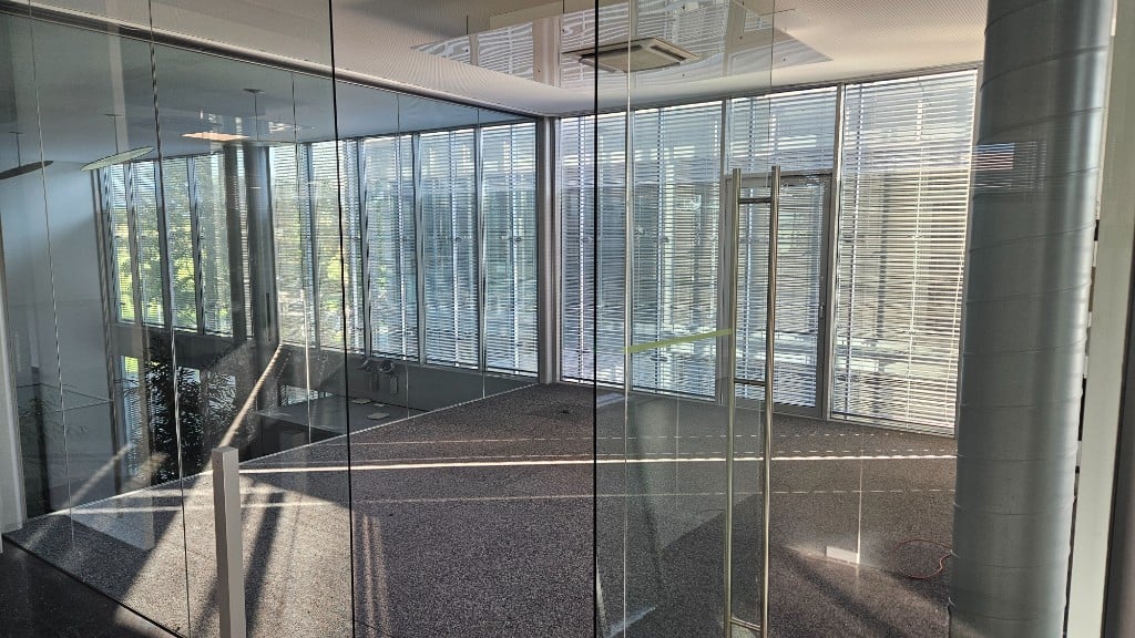 Blick durch die Glasfront auf eine freie Bürofläche mit viel Tageslicht im GlessHub