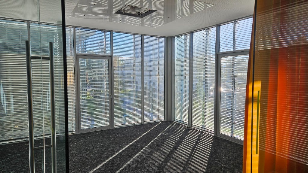 Bright corner office with glass facade, blinds and carpet at GlessHub